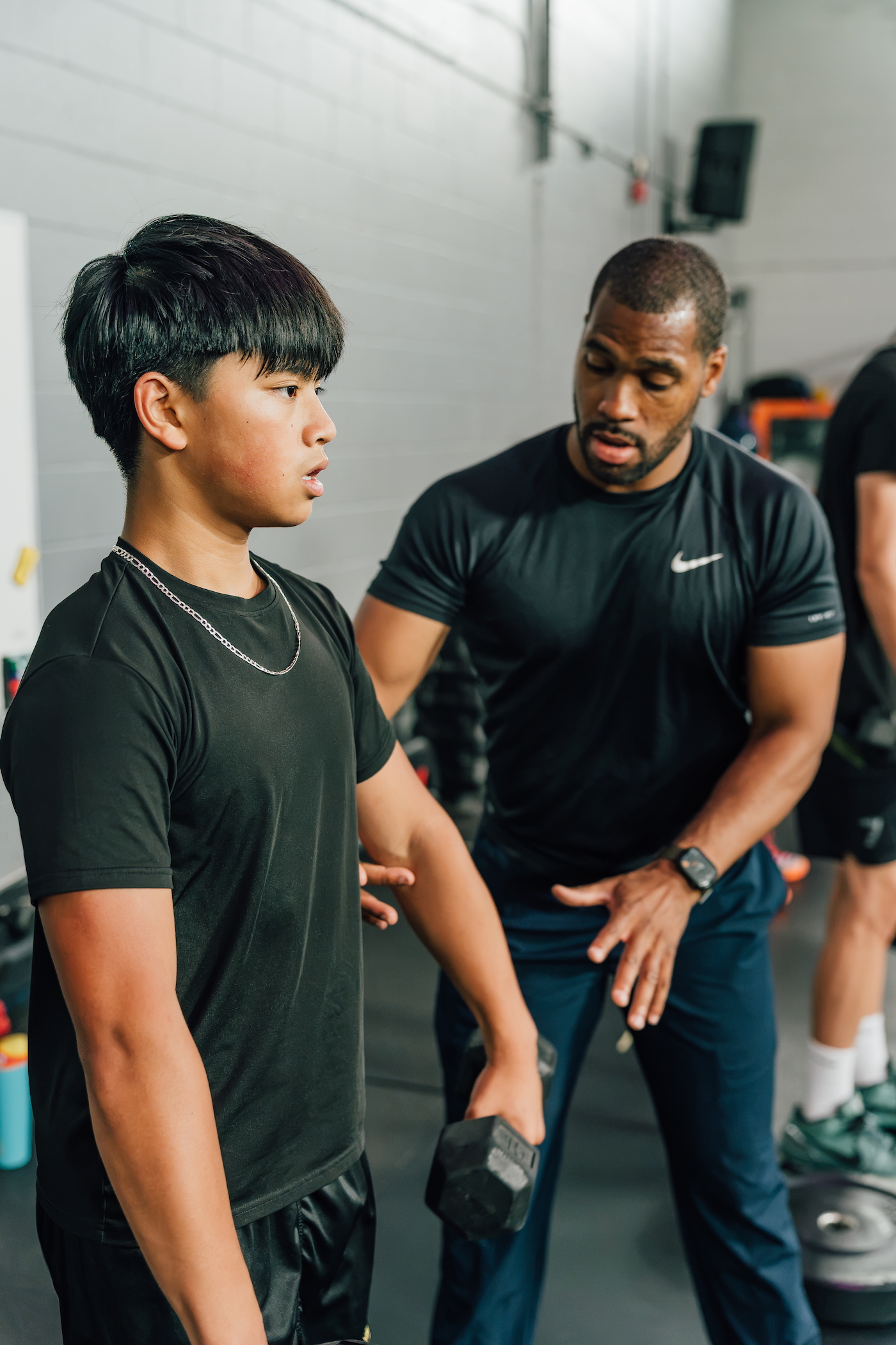 Coach guiding an athlete through a resisted sprint drill on the turf